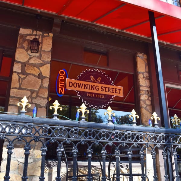 Exterior of Downing Street Pour House with a red awning, stone facade, and an "OPEN" sign.