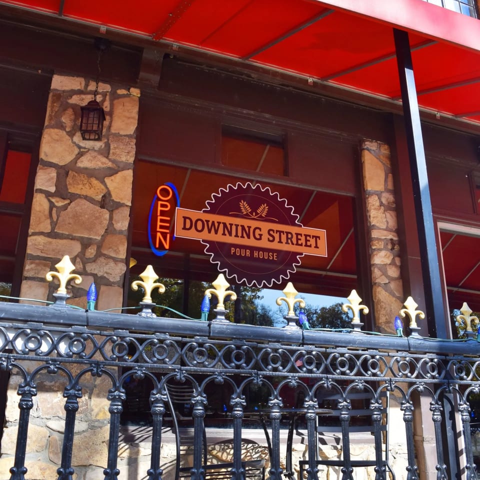 Exterior of Downing Street Pour House with a red awning, stone facade, and an "OPEN" sign.