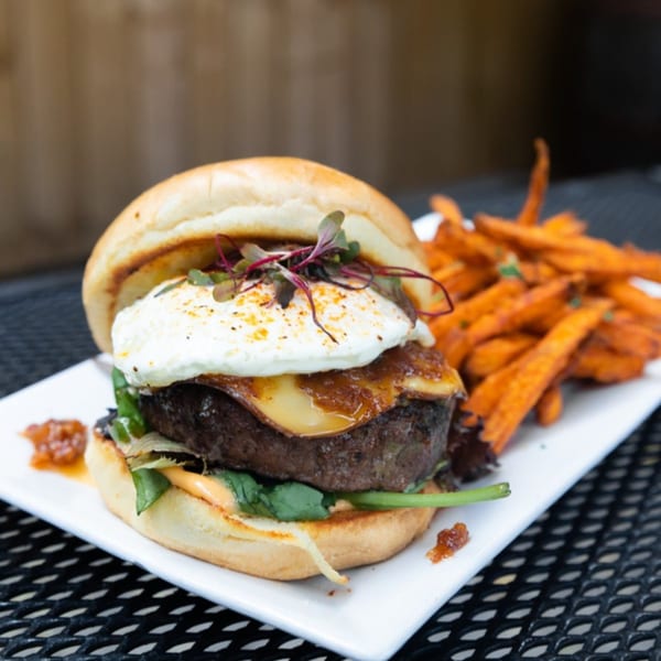 A Downing Street Pour House burger with a fried egg, cheese, and sweet potato fries.